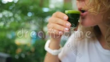 年轻女子喝麦草汁。 健康的绿色素面素是维生素的最佳来源。